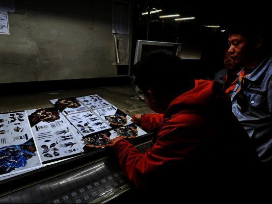 工作人员正在对《崩坏：星穹铁道》纪念画册进行现场校色处理，桌上摆放着印刷样张和专业色卡