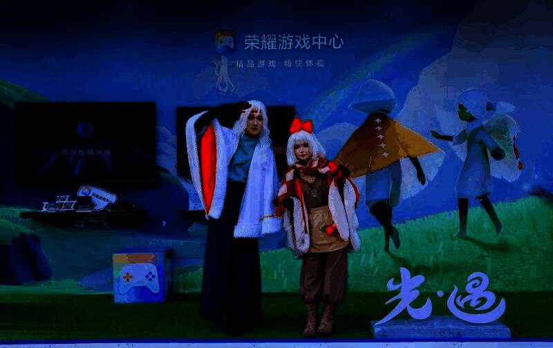 玩家在荣耀游戏中心展区使用手柄游玩《光·遇》，周围观众围观体验