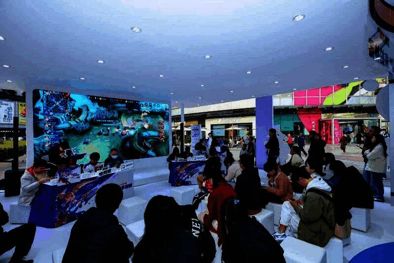 《决胜巅峰》赛事现场观众热情欢呼，背景大屏显示荣耀GT系列手机宣传画面