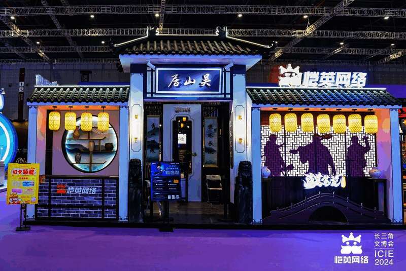 恺英网络展台全景图，灯光炫丽，人群聚集，背景为《盗墓笔记：启程》主题布景