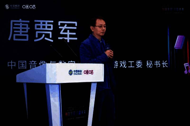 唐贾军在论坛上发表演讲，背景大屏展示2024年中国游戏市场数据图表，包括收入与用户增长趋势