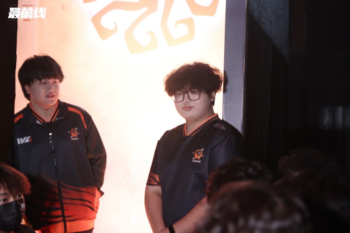 FPX.ZQ战队集体训练场景，Alpaca（左二）正与队友围看战术屏幕，手指指向画面中的监管者走位路径，神情投入