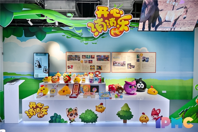 中国音数协游戏IP陈列馆实景照片：通透玻璃展柜中陈列《开心消消乐》十周年纪念版莱萌鸡手办，背景LED屏滚动播放游戏经典画面与‘国民消除IP’荣誉标识